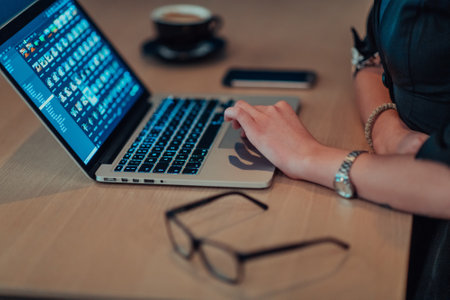 Close up photo of businesswoman sitting in a cafe while focused on working on a laptop and participating in an online meetings. Selective focus.の写真素材