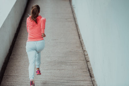 Women in sports clothes running in a modern urban environment. The concept of a sporty and healthy...