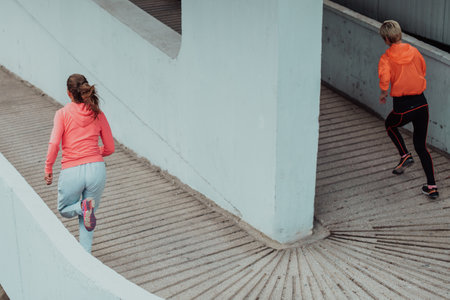 Two women in sports clothes running in a modern urban environment. The concept of a sporty and healthy lifestyleの写真素材