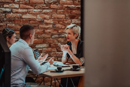 Happy businesspeople smiling cheerfully during a meeting in a coffee shop. Group of successful business professionals working as a team in a multicultural workplace.の写真素材