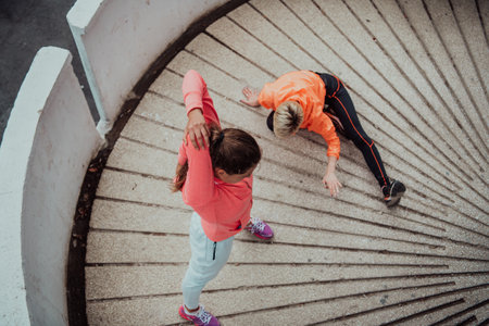 Two women warming up together and preparing for a morning run in an urban environment. Selective focusの写真素材