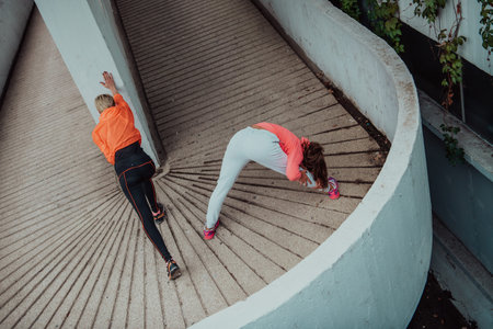 Two women warming up together and preparing for a morning run in an urban environment. Selective focusの写真素材