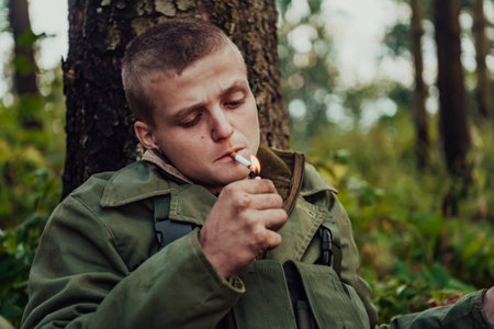 Terrorist have a break and smoke cigarette in forest during battleの写真素材