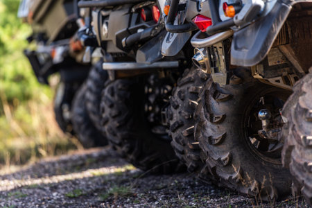 Close-up tail view of ATV quad bike on dirt country road. Dirty wheel of AWD all-terrain vehicle. Travel and adventure concept.の写真素材
