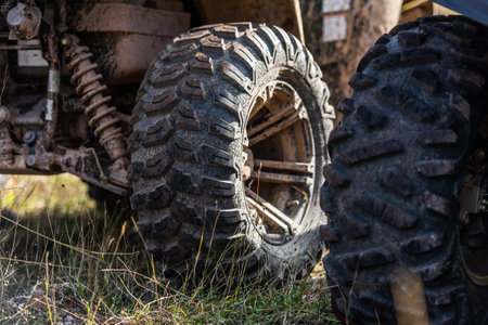 Close-up tail view of ATV quad bike on dirt country road. Dirty wheel of AWD all-terrain vehicle. Travel and adventure concept.の写真素材