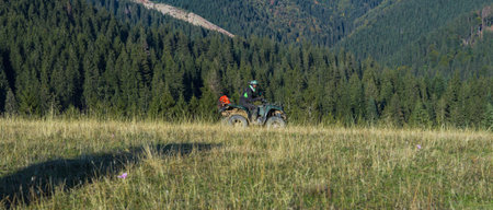 A man driving a quad ATV motorcycle through beautiful meadow landscapes