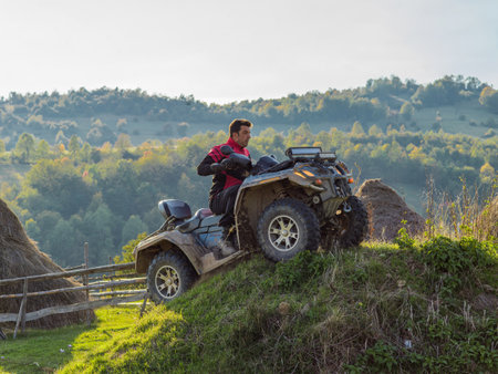 A man driving a quad ATV motorcycle through beautiful meadow landscapesの写真素材