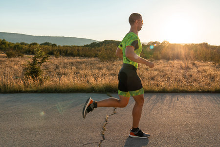 Triathlete in professional gear running early in the morning, preparing for a marathon, dedication...