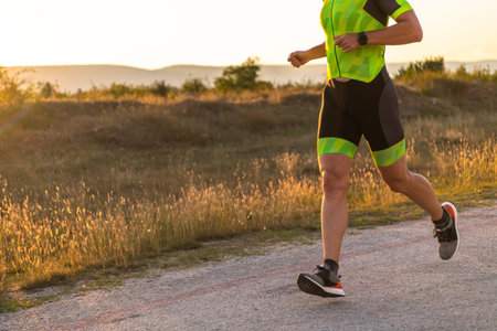 Triathlete in professional gear running early in the morning, preparing for a marathon, dedication...