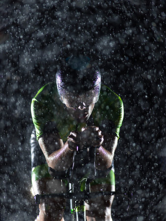 A triathlete braving the rain as he cycles through the night, preparing himself for the upcoming...