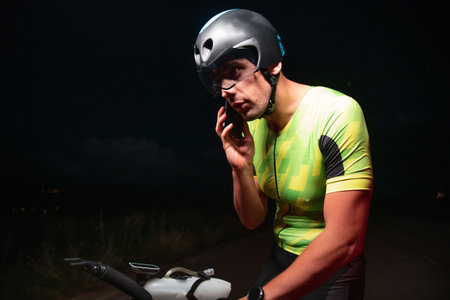 A triathlete using a smartphone while taking a break from a hard nights cycling trainingの写真素材