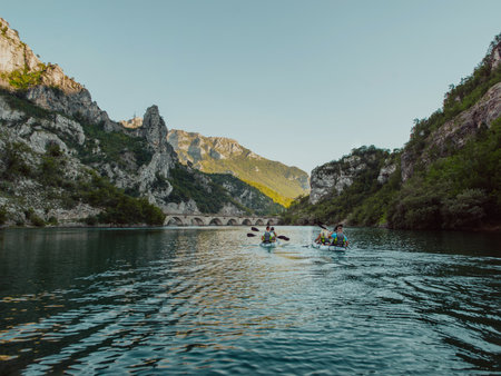 A group of friends enjoying having fun and kayaking while exploring the calm river, surrounding forest and large natural river canyonsの写真素材