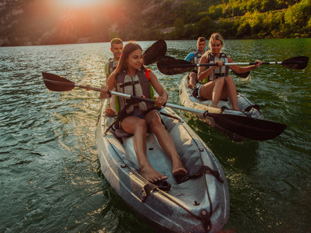 A group of friends enjoying fun and kayaking exploring the calm river, surrounding forest and large natural river canyons during an idyllic sunset.の写真素材
