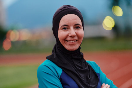 A Muslim woman with a burqa, an Islamic sportswoman resting after a vigorous training session on the marathon course. A hijab woman is preparing for a marathon competitionの写真素材