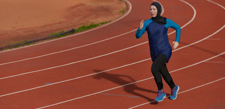A muslim woman in a burqa sports muslim clothes running on a marathon course and preparing for upcoming competitionsの写真素材