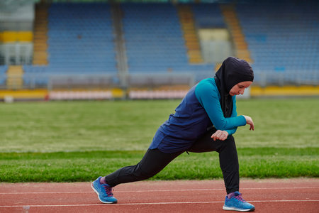 A Muslim woman in a burqa, an Islamic sports outfit, is doing body exercises, stretching her neck,...