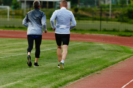 An inspiring and active elderly couple showcase their dedication to fitness as they running together on a lush green field, captured in a close-up shot of their legs in motion.の写真素材