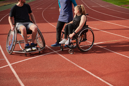 A woman with a disability in a wheelchair talking after training with a woman wearing a hijab and a man in a wheelchairの写真素材
