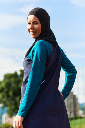 A Muslim woman with a burqa, an Islamic sportswoman resting after a vigorous training session on the marathon course. A hijab woman is preparing for a marathon competitionの写真素材