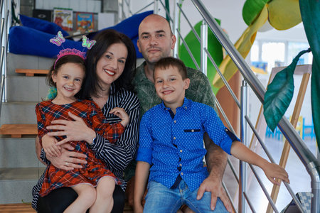 Portrait of a happy family. Photo of parents with children in a modern preschool classroom....