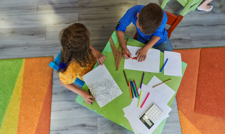 Cute girl and boy sit and draw together in preschool institutionの写真素材