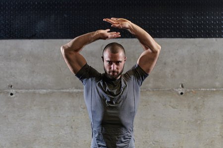 A muscular man working stretching exercises for his arms and body muscles in modern gym
