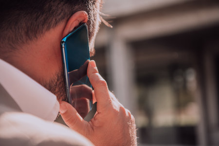 A businessman using his smartphone outdoors, showcasing the seamless integration of technology and mobility in modern professional life.の写真素材