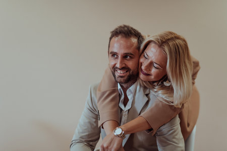 A business couple posing for a photograph together against a beige backdrop, capturing their professional partnership and creating a timeless image of unity and success.の写真素材