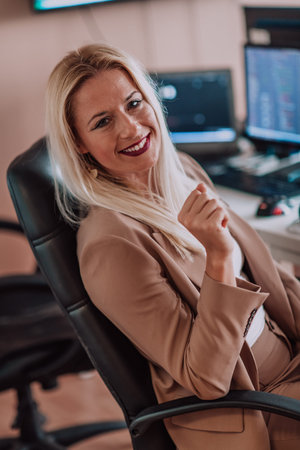 A businesswoman sitting in a programmers office surrounded by computers, showing her expertise and...