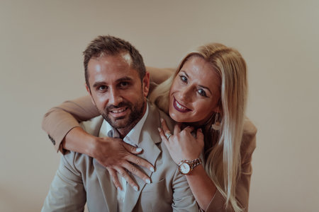 A business couple posing for a photograph together against a beige backdrop, capturing their professional partnership and creating a timeless image of unity and success.の写真素材