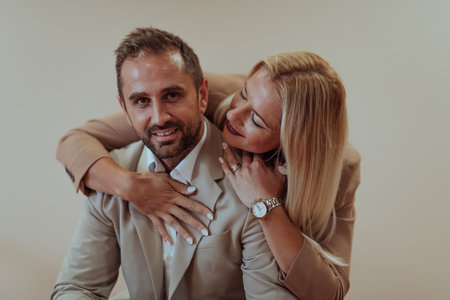 A business couple posing for a photograph together against a beige backdrop, capturing their professional partnership and creating a timeless image of unity and success.の写真素材