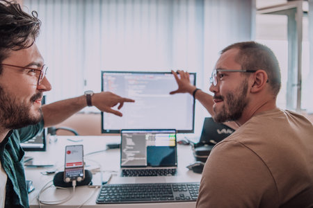 Programmers engrossed in deep collaboration, diligently working together to solve complex problems and develop innovative mobile applications with seamless functionality.の写真素材
