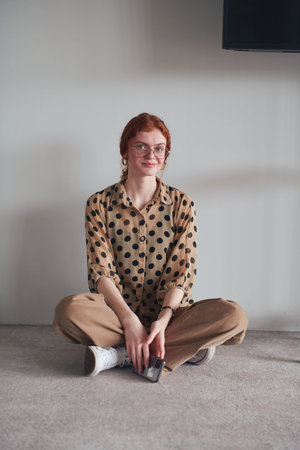 A young and fashionable businesswoman sitting and taking a moment to relax while using her...