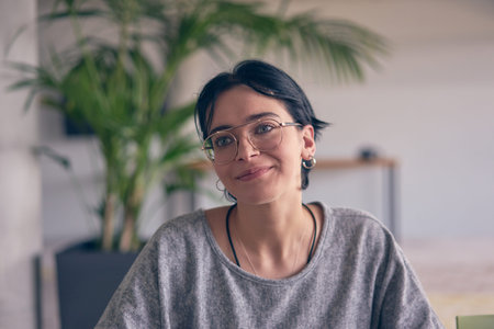 In a modern office, a young smile businesswoman with glasses confidently explains and presents...