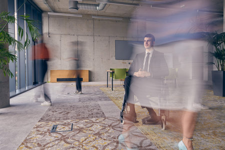 A businessman in a wheelchair in a modern office, surrounded by his colleagues who are portrayed...