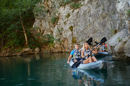 A group of friends enjoying having fun and kayaking while exploring the calm river, surrounding forest and large natural river canyonsの写真素材
