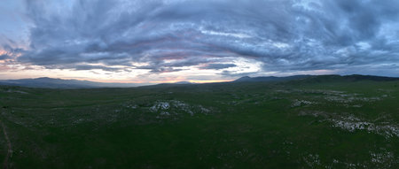 Aerial view of countryside landscape. Clouds with shades of purple, orange and green vegetation....