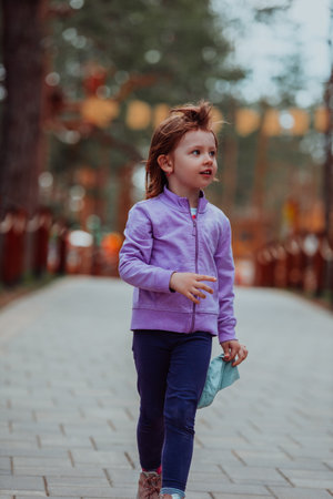 A little girl playing in the park. The concept of family socializing in the park. A girl swings on a swing, plays creative gamesの写真素材