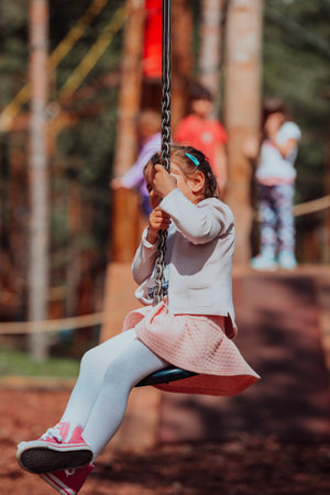 A little girl playing in the park. The concept of family socializing in the park. A girl swings on a swing, plays creative gamesの写真素材