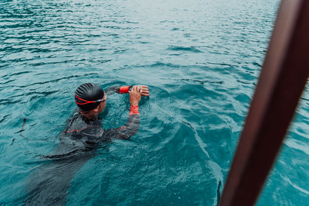 A triathlete in a professional swimming suit trains on the riverの写真素材