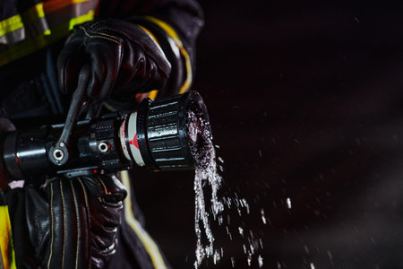 Firefighter using a water hose to eliminate a fire hazard. Team of firemen in the dangerous rescue mission.の写真素材