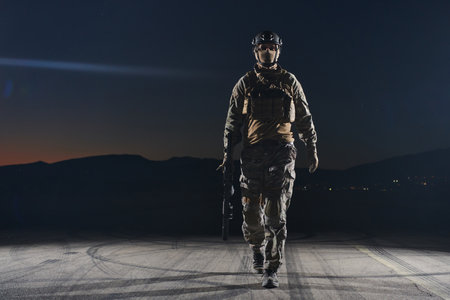 A professional soldier in full military gear striding through the dark night as he embarks on a perilous military missionの写真素材