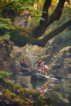 A group of friends enjoying having fun and kayaking while exploring the calm river, surrounding forest and large natural river canyonsの写真素材