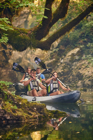 A group of friends enjoying having fun and kayaking while exploring the calm river, surrounding forest and large natural river canyonsの写真素材