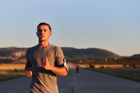 A young handsome man running in the early morning hours, driven by his commitment to health and fitnessの写真素材