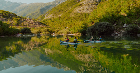A group of friends enjoying having fun and kayaking while exploring the calm river, surrounding forest and large natural river canyonsの写真素材