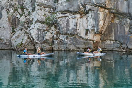 A group of friends enjoying having fun and kayaking while exploring the calm river, surrounding forest and large natural river canyonsの写真素材
