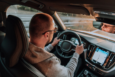 A man with a sunglasses driving a car at sunset. The concept of car travelの写真素材