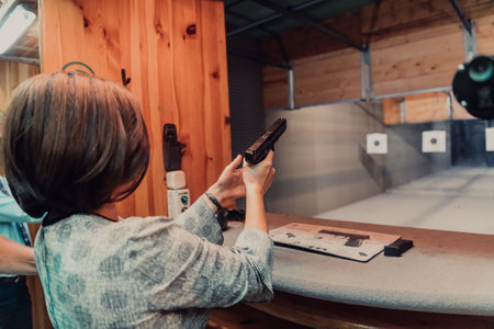 A woman practices shooting a pistol in a shooting range while wearing protective headphonesの写真素材