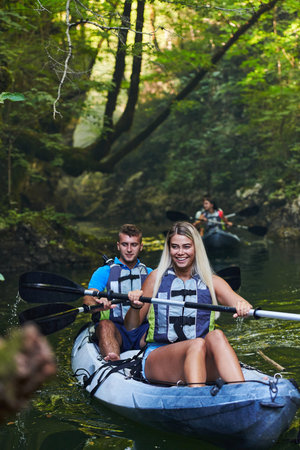 A group of friends enjoying having fun and kayaking while exploring the calm river, surrounding forest and large natural river canyonsの写真素材